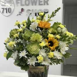 Mixed bouquet in a dark metal vase with green, white, and yellow flowers