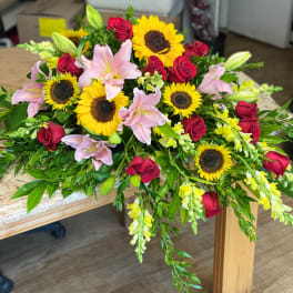 Bouquet of red roses, pink lilies, and sunflowers on a table