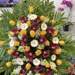 Large standing spray with yellow roses, burgundy orchids, and white daisies