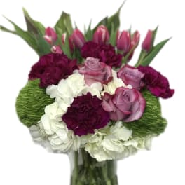 Bouquet of pink tulips, roses, and carnations in a glass vase