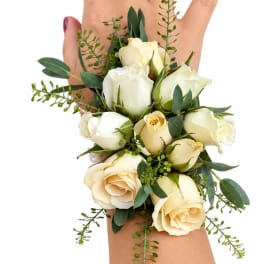 Cream rose wrist corsage with green foliage on a person's wrist