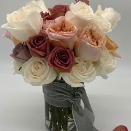 Bouquet of cream, blush, and burgundy roses in a glass vase