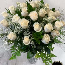 Tall arrangement of white roses and baby’s breath in a clear glass vase