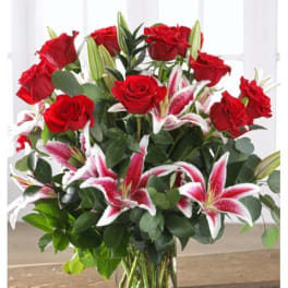 Red roses and pink stargazer lilies in a clear glass vase