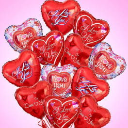 Cluster of red heart-shaped balloons with love messages on a pink background