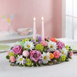 Low floral centerpiece with two pink candles and pastel flowers