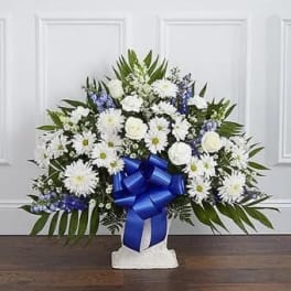 White floral standing spray with a blue ribbon on a white easel