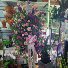 Large pink and purple floral standing arrangement with a ribbon bow