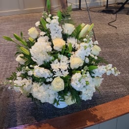 White floral arrangement with roses, lilies, and hydrangeas in a low vase