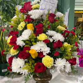 Red roses, white daisies, and yellow carnations in a bronze vase