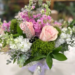 Pink roses and white flowers arranged with purple blooms in a bouquet