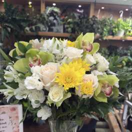 Mixed bouquet of white and yellow flowers in a clear glass vase