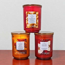 Three scented candles in glass jars stacked on a table