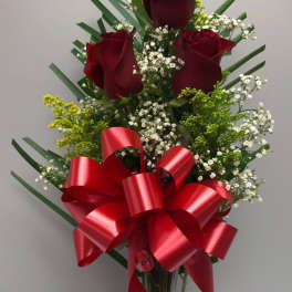 Red roses in a clear vase with a large red ribbon