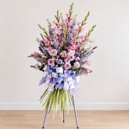 Tall pink and lavender floral arrangement with ribbon on a stand
