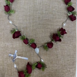 Rose petal rosary with silver beads and a crucifix on burlap