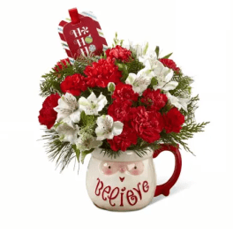 Red and white floral arrangement in a mug with a holiday tag