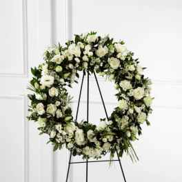 White floral wreath on a black stand