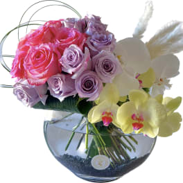 Pink and lavender roses with white orchids in a glass vase
