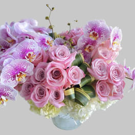 Pink roses and speckled orchids in a glass vase
