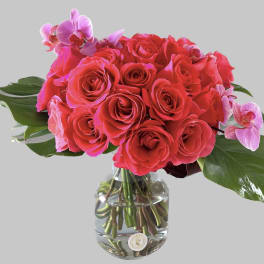 Pink roses with orchid accents in a clear glass vase