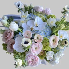 Pastel bouquet with white orchids, pink ranunculus, and pale roses