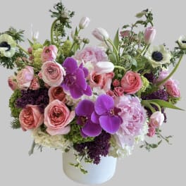 Pink and white floral arrangement with orchids and roses in a white vase