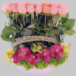 Pink roses and magenta orchids arranged in a basket with moss.