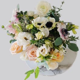 Bouquet of white, blush, and peach flowers in a round vase