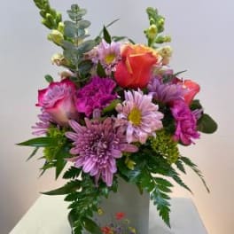 Mixed bouquet of pink and orange flowers in a gray vase