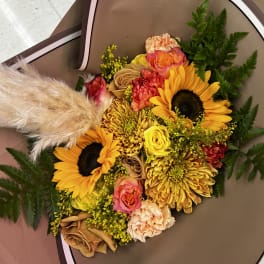 Bouquet of sunflowers, roses, and chrysanthemums wrapped in brown paper