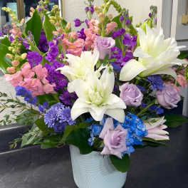 Colorful mixed bouquet in a white vase with white lilies and pastel roses