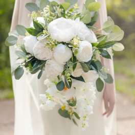 Cascading bridal bouquet of white flowers with lush green foliage accents