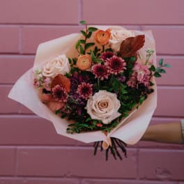 Bouquet of pale roses and pink-purple flowers wrapped in blush paper