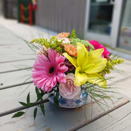 Mixed bouquet in a blue-and-white ceramic bowl with pink and yellow blooms