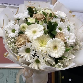 Bouquet of white daisies and beige roses wrapped in white paper
