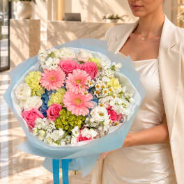 Woman holding a pastel bouquet of pink, white, and yellow flowers