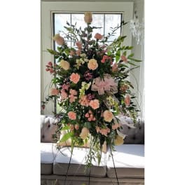 Tall pink and cream floral arrangement on a stand with a ribbon bow