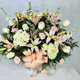 Large bouquet of pink lilies, white roses, and hydrangeas with a peach ribbon