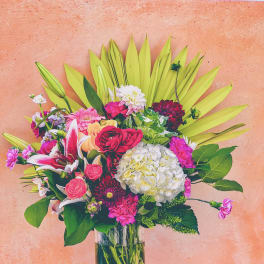 Mixed bouquet of pink, white, and red flowers in a clear glass vase