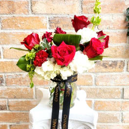 Red roses and white carnations in a glass vase with a black ribbon