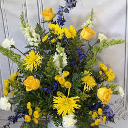Yellow and blue floral arrangement in a white vase