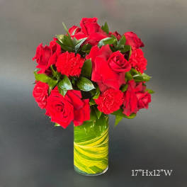 Red roses and carnations in a tall glass vase