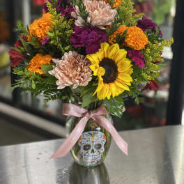 Colorful bouquet in a glass vase with a pink ribbon and skull decal