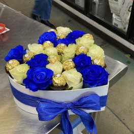 Blue and white roses with gold-wrapped chocolates in a white gift box