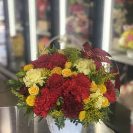 Basket arrangement of red, yellow, and cream flowers