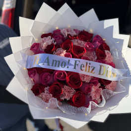 Bouquet of red roses and pink carnations with a "Te Amo! Feliz Día" ribbon