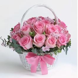 Pink roses arranged in a white basket with a pink ribbon