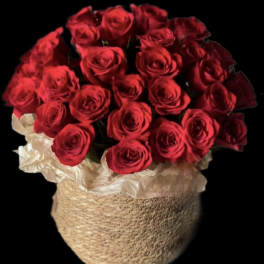 Bouquet of red roses in a woven basket wrapped with white paper