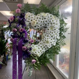 Heart-shaped floral wreath with white daisies and purple roses on an easel